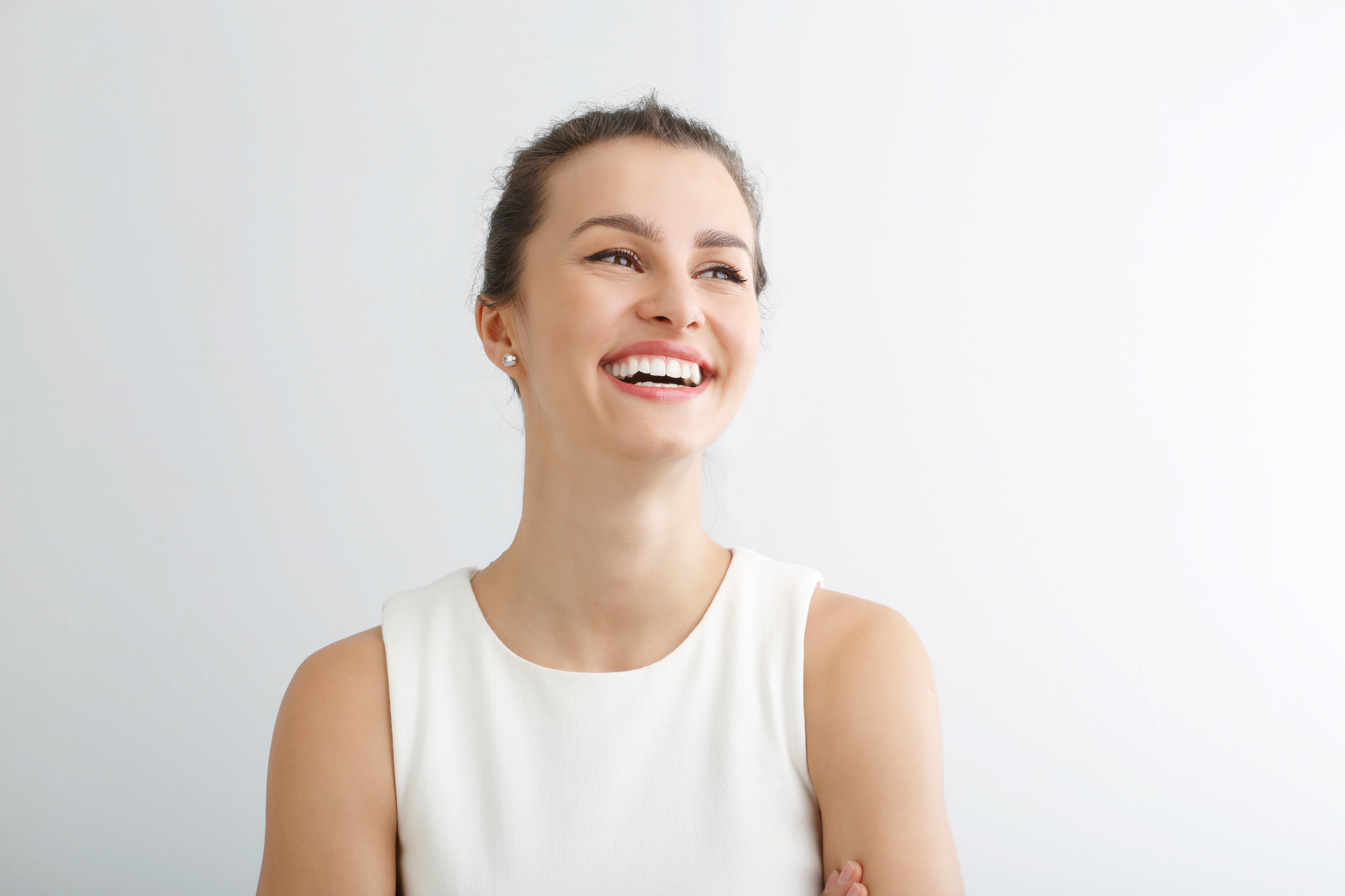 Mulher com vestido branco sorrindo olhando para o lado