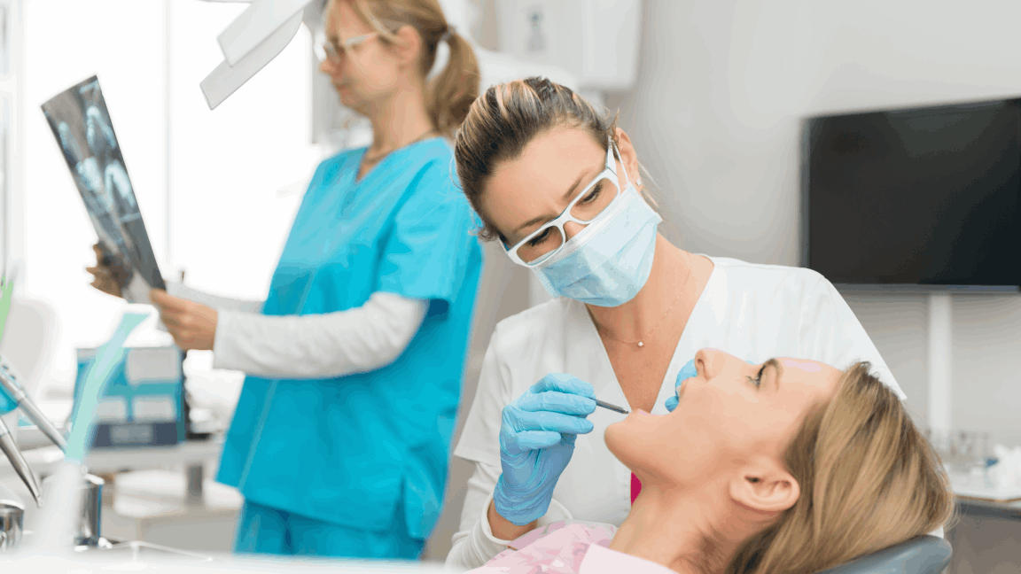 O espelho do dentista na boca de jovem reflete a parte posterior dos dentes da frente