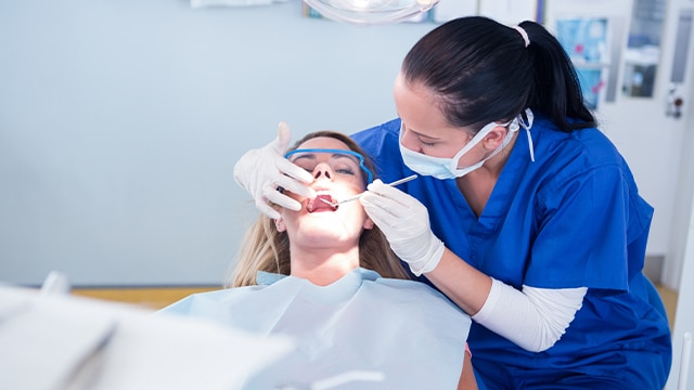Dentista examinando os dentes de uma menina