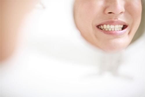 Reflexo de sorriso em espelho de aumento, destacando a dentição para identificação de sintomas de deficiência mineral.