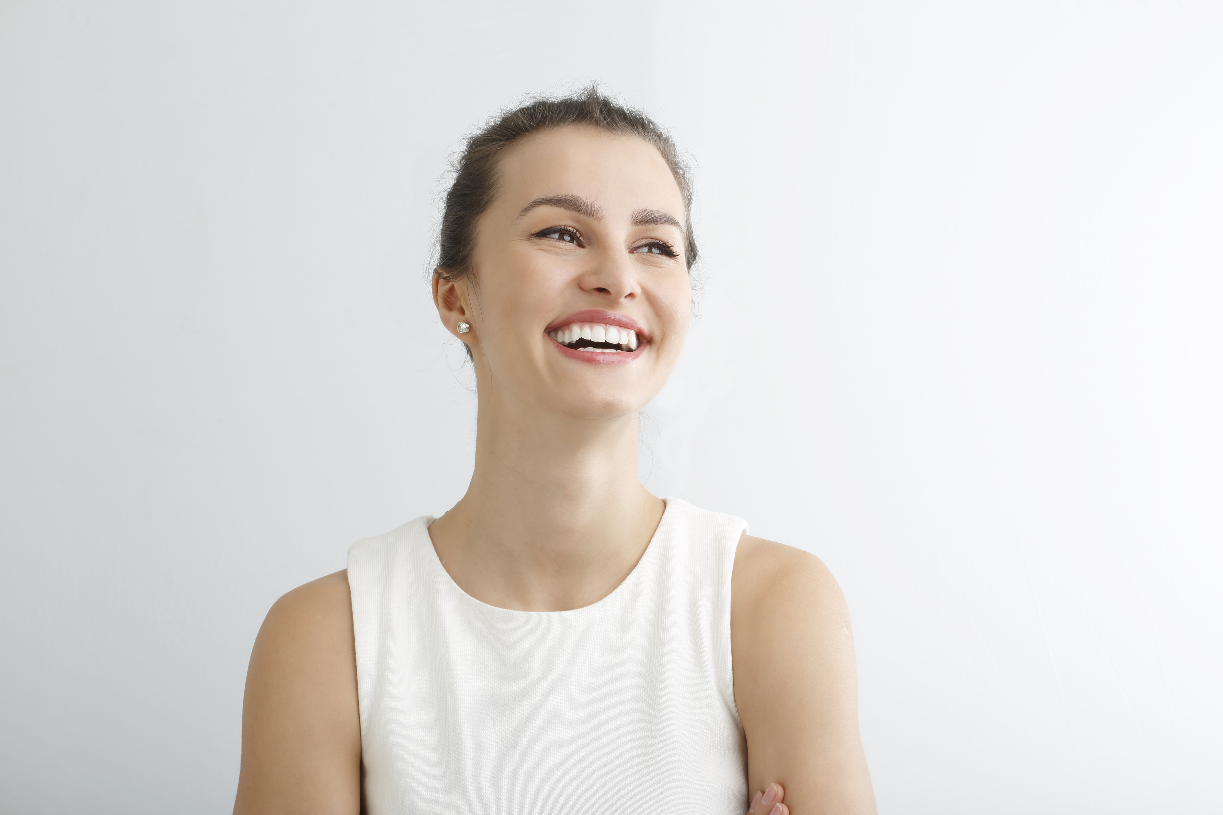 Mulher com vestido branco sorrindo olhando para o lado