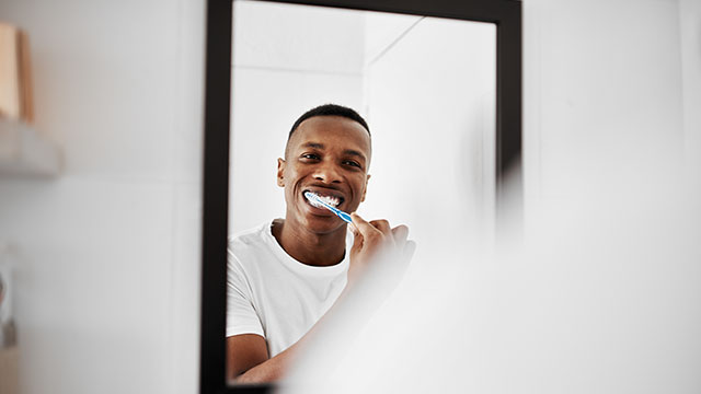 Homem lavando a escova de dente no banheiro