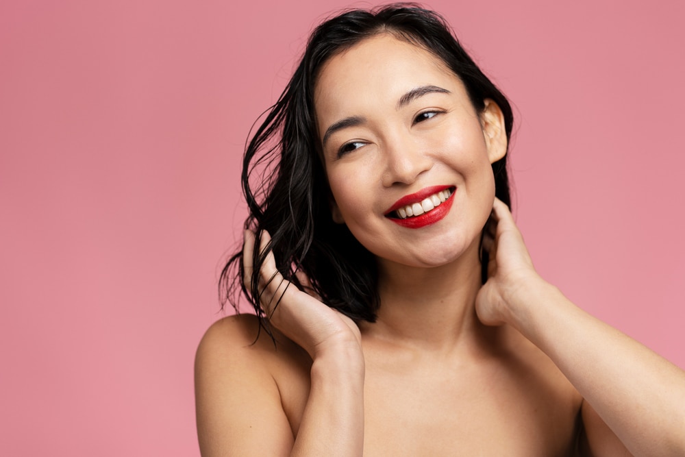 Mulher sorridente com batom vermelho vivo, representando cores de batom que valorizam o sorriso.