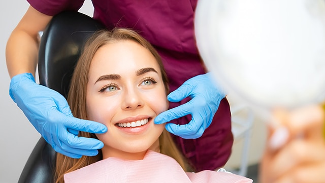 Mulher sorrindo para o espelho após usar a sua escova interdental