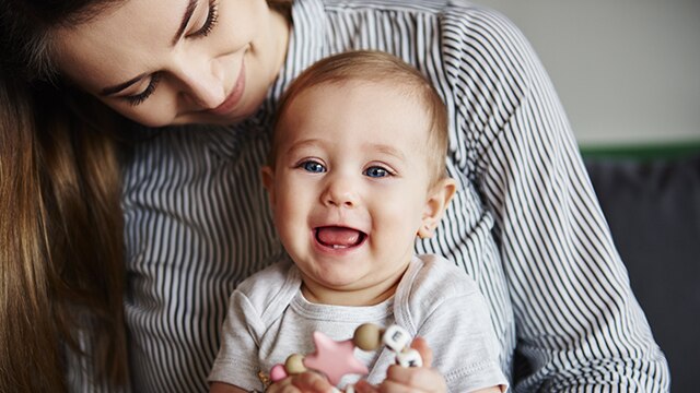 Mamãe com bebê no colo observando se ele apresenta sintomas de fenda palatina