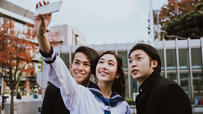 Três jovens sorrindo enquanto tiram selfie