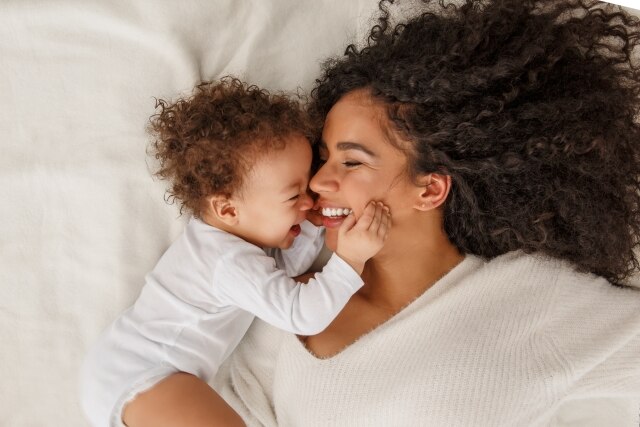 bebê e mãe rindo na cama