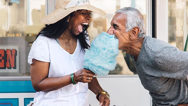 Casal sênior rindo e comendo algodão doce