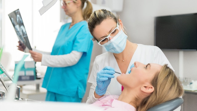 Mulher em consultório odontológico recebendo anestesia no dentista para um procedimento