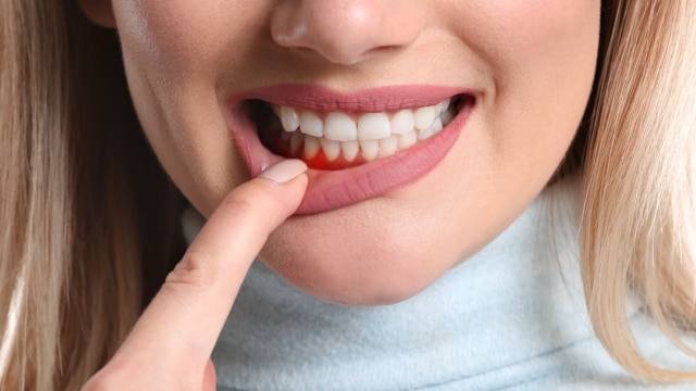 homem jovem, vestindo uma camiseta branca, segurando um fio dental em frente a um espelho