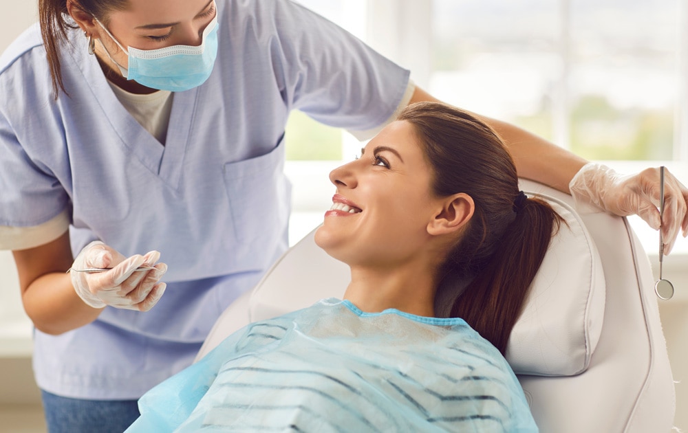 Profissional de odontologia orienta paciente, lembrando a importância do check-up no dia mundial da saude bucal.