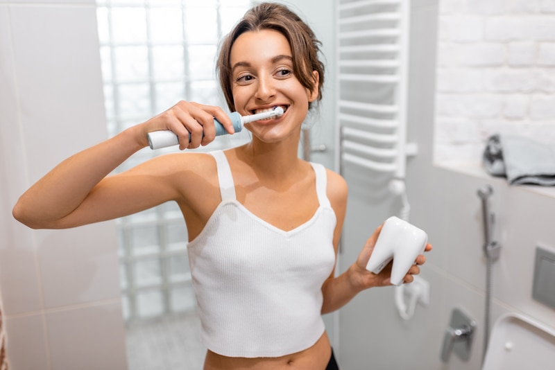 Menina se perguntando se a escova de dente elétrica é melhor do que comum