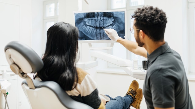 Mulher deitada na cadeira do dentista fazendo o tratamento de endodontia