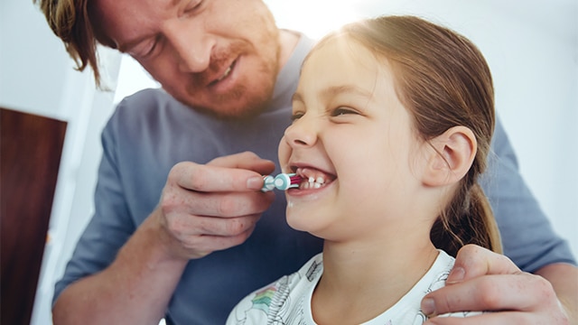 A mãe abre a boca do bebê para examinar os primeiros dentes.