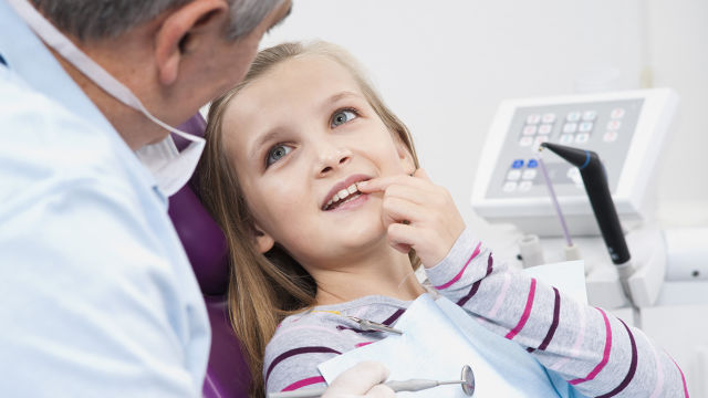 Menina mostrando os dentes para o dentista