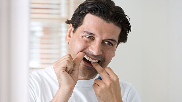 Homem passando fio dental