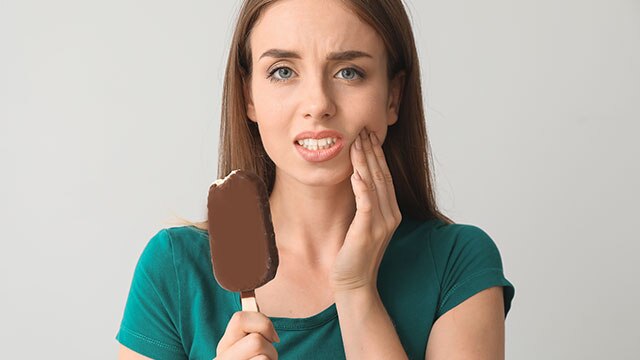 Uma garota com sensibilidade comendo sorvete