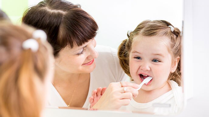Mãe escovando os dentes da filha