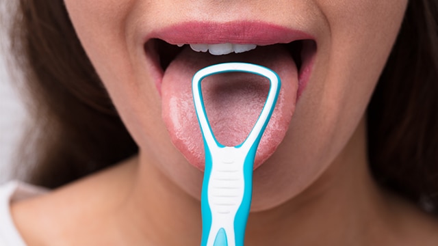 Mulher de cachecol olhando para o horizonte com uma xícara de chá quente entre as mãos