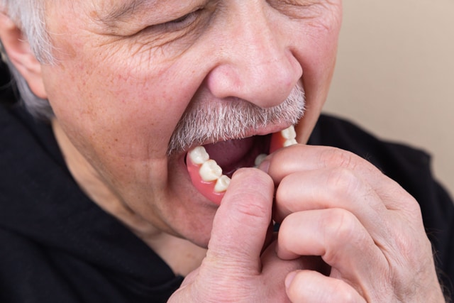 Um adulto mais velho coloca os dentes.
