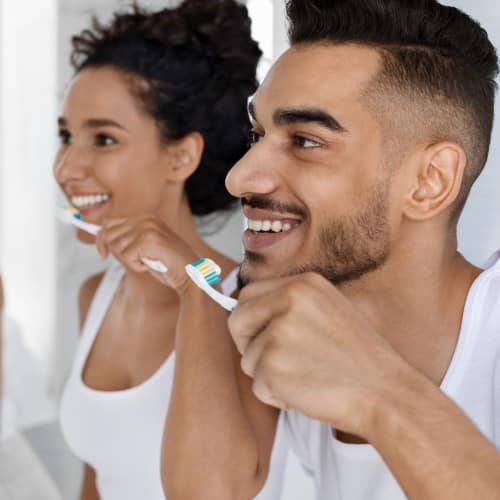 Mulher e homem escovando os dentes no banheiro