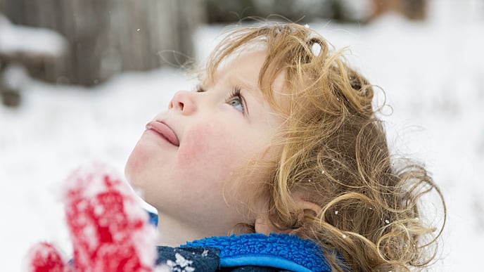 Criança em meio dela neve com a língua fora