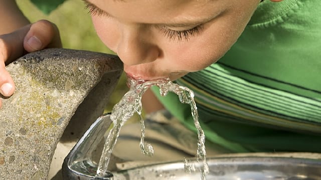 Uma criança de beber água de uma fonte