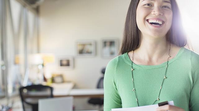 mulher trabalhando e sorrindo na seu escritório
