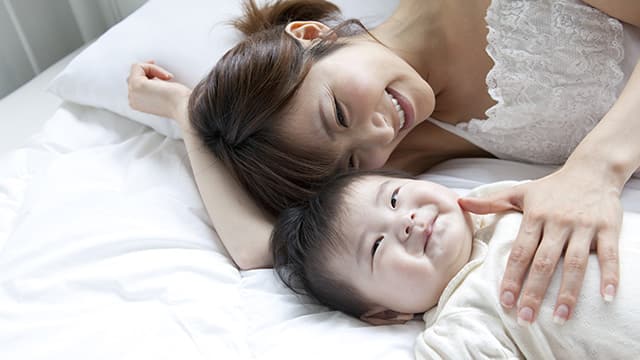 Mãe e bebê sorrindo na cama