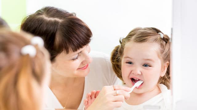 Mãe escovando os dentes da filha