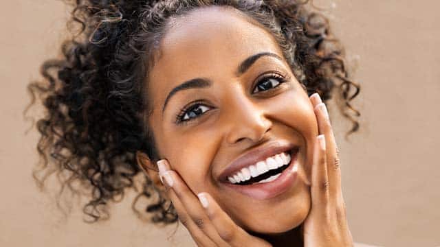 Mulher sorrindo, com os dentes bem brancos por ter usado clareador dental