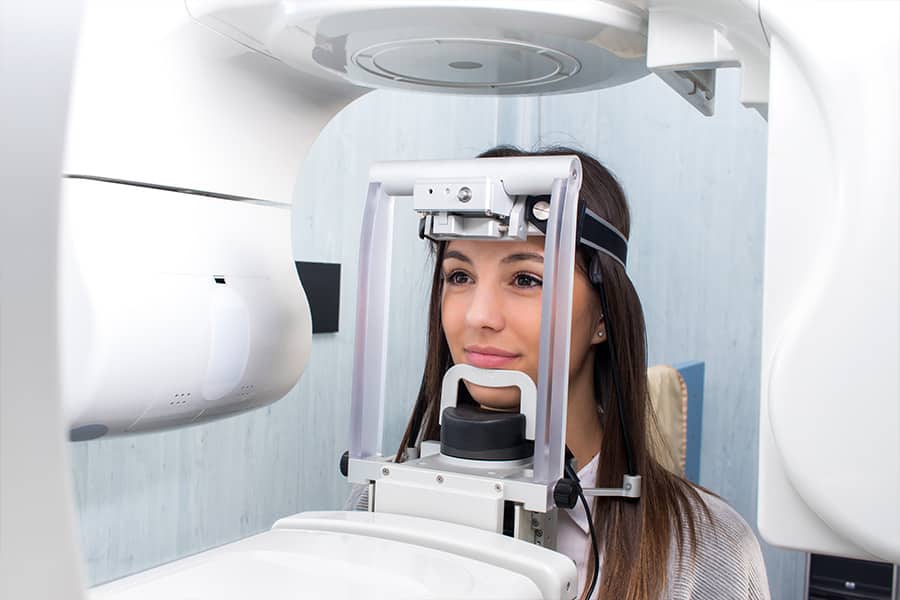 Perto da cabeça de uma garota, a fazer uma tac dentária com uma máquina de raios-x panorâmica cefalométrica na clínica.