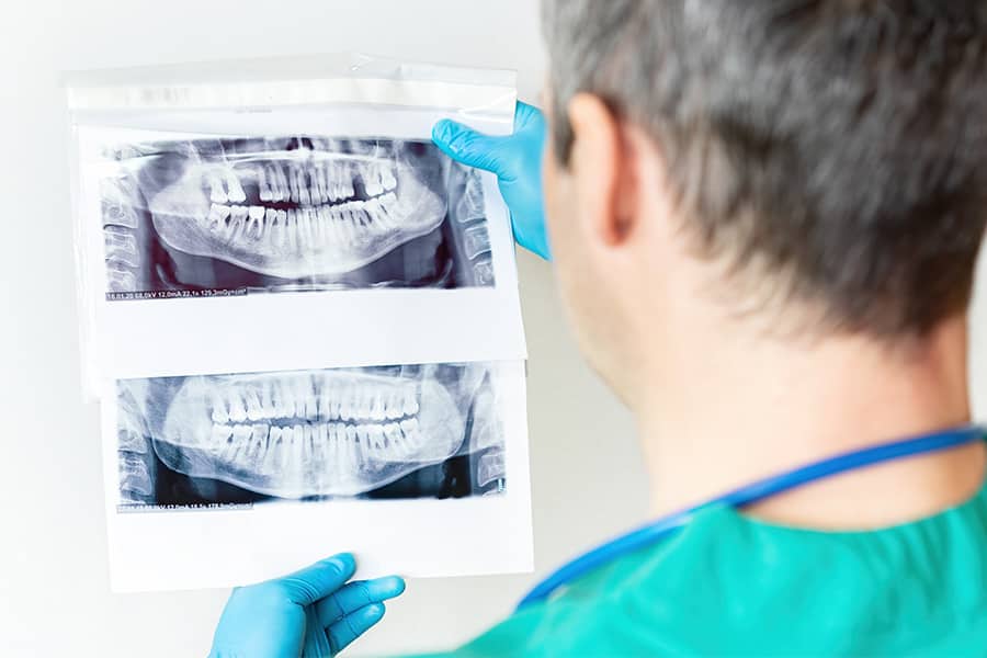 Dentista examina raios-X panorâmica dos dentes da mandíbula superior e inferior