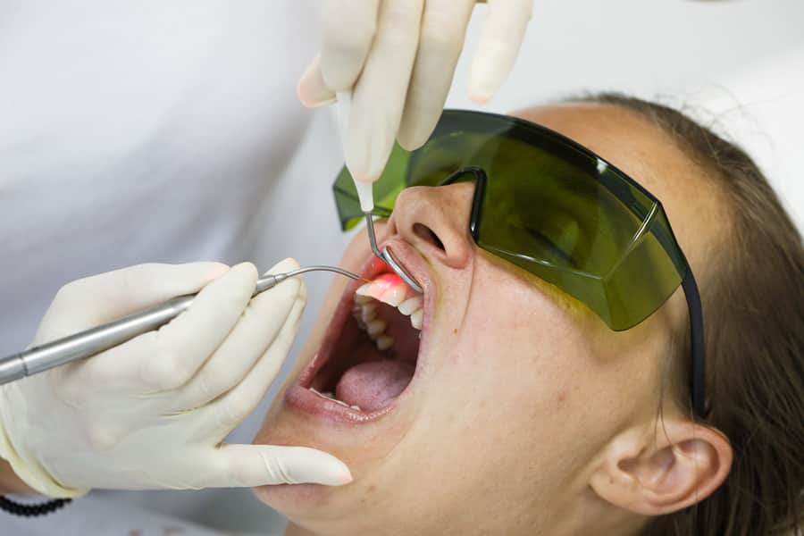 Dentista usando um laser dental para cuidados periodontais