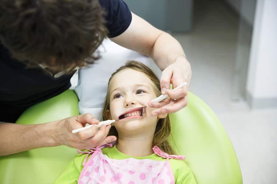 Menina no consultório de dentistas pediátricos em seu check-up regular