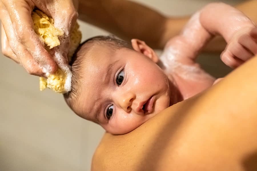 Banho do bebê recém-nascido com esponja especial para cuidar do bebê.