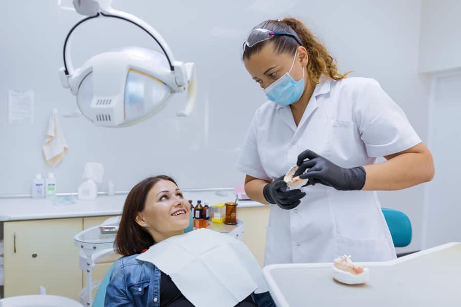 dentista mostrando modelo de mandíbula a paciente