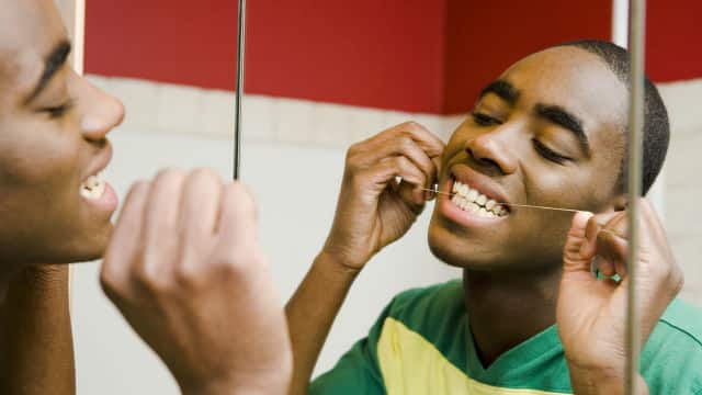 Homem passando fio dental nos dentes
