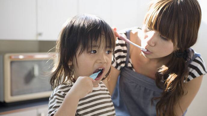 mãe e filha escovando dentes com creme dental branqueador