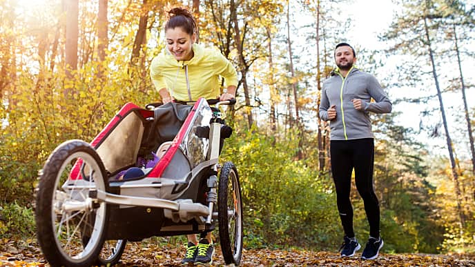 Casal exercitando juntos no parque empurrando seu bebê em um carrinho de bebé