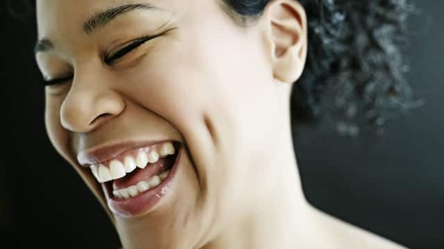 Mulher, negra, com idade aproximada de 30 anos, sorrindo.