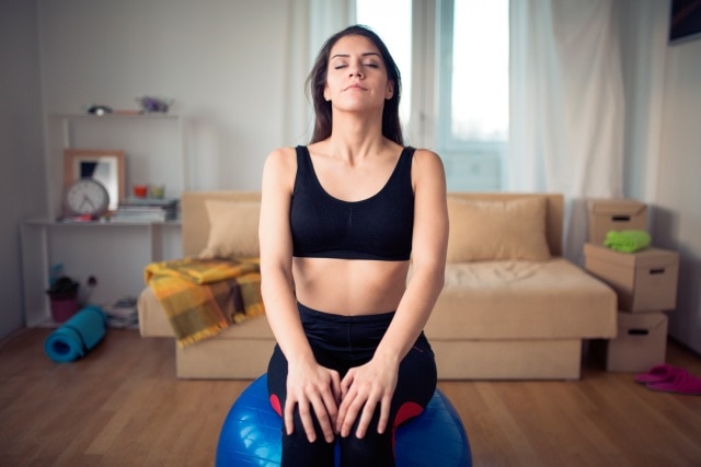  Mulher sentada fazendo uma pausa entre seus exercícios para fazer em casa