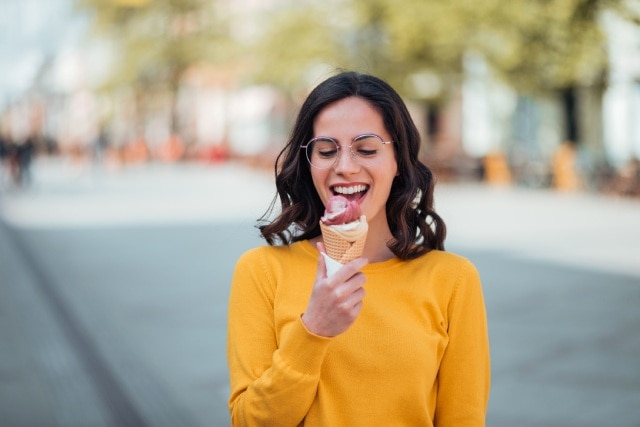 Mulher sorridente ao ar livre saboreando um sorvete italiano
