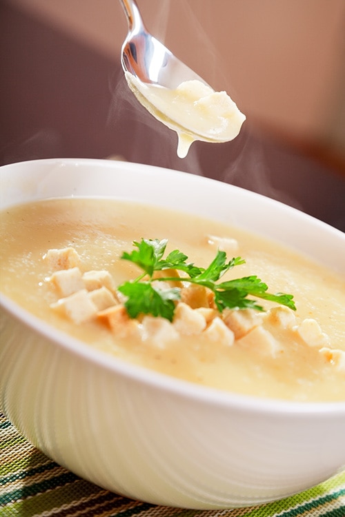 Uma sopa de legumes cremosa, servida em uma tigela com croutons, ideal para uma refeição reconfortante e nutritiva.